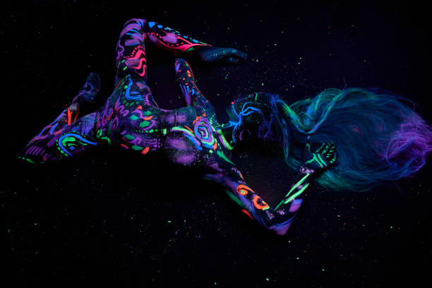 Art woman body art on the body dancing in ultraviolet light. Bright abstract drawings on the girl body neon color. Fashion and art woman Art woman body art on the body dancing in ultraviolet light. Bright abstract drawings on the girl body neon color. Fashion and art woman paint neon color neon light ultraviolet light stock pictures, royalty-free photos & images