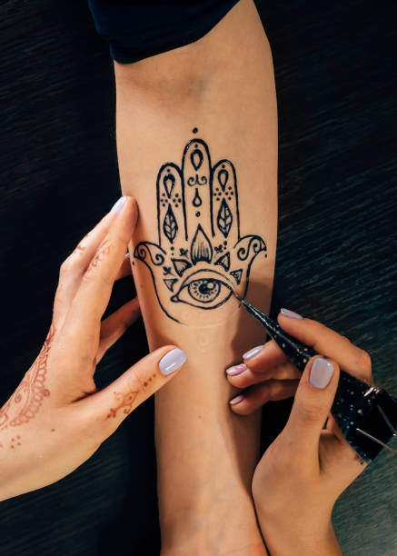 Artist applying henna mehndi tattoo on female hand stock photo