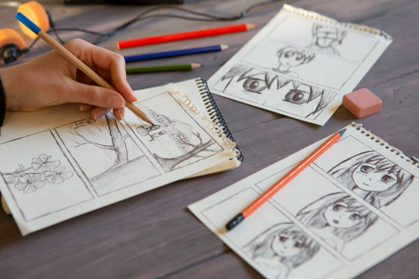 Artist drawing an anime comic book in a studio. Wooden desk, natural light. Creativity and inspiration concept. stock photo