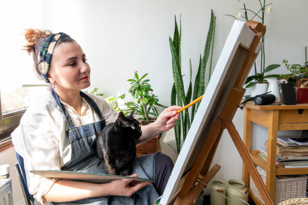 Artist enjoying painting with her black cat. stock photo