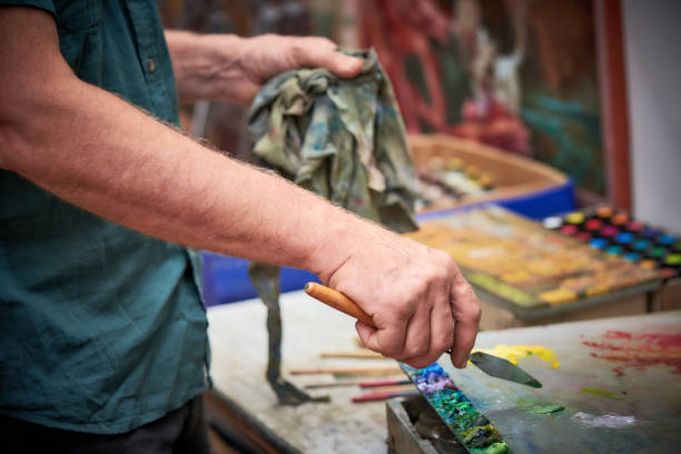 artist holding palette knife in studio stock photo