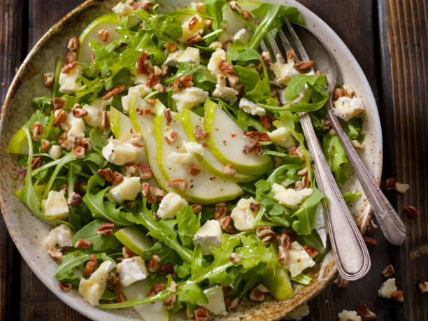 Arugula, Pear and Brie Salad with Walnuts Arugula, Pear and Brie Salad with Walnuts and Herb Oil Dressing arugula stock pictures, royalty-free photos & images