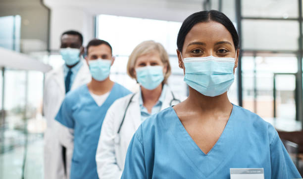As medical professionals, we have such an important job to do Portrait of a group of medical practitioners wearing face masks while standing together in a hospital medical occupation stock pictures, royalty-free photos & images
