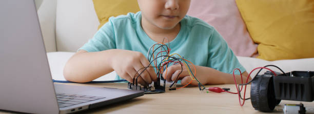 Asia people home school young small kid happy smile laugh self study online lesson excited make AI circuit toy. STEM STEAM digital class on laptop for active children play arduino enjoy fun hobby. stock photo