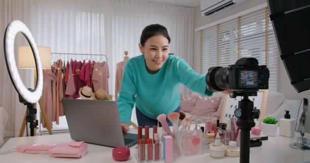 Asia SME owner, seller woman micro influencer, happy youtuber prepare record live video media arrange camera at home studio. Vlogger selfie shoot enjoy hobby work smile in reel story sale page app. stock photo