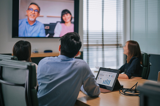 Asia white collar worker financial advisor having video conference videocall with company staff meeting discussion In the Conference Room Board of Directors Have Video Call with Foreign Investor. Business Meeting with Mergers and acquisitions