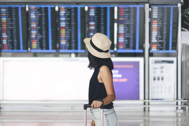 Asian adult tourist woman with travel luggage in airport terminal on day stock photo