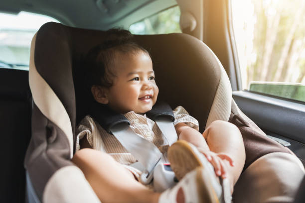 Asian Baby Toddler girl sitting in car seat and looking through window. Infant baby with safety belt in vehicle. Safety car. Family travel concept stock photo