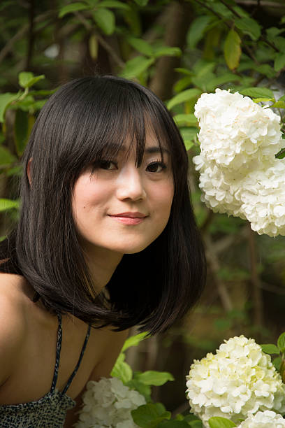 Asian Beauties Beautiful asian woman poses next to another Asian beauty, the Chinese snowball, Viburnum opulus ::::: asian beauties : stock pictures, royalty-free photos & images