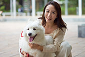 アジアン ビューティー ガーデンで屋外カメラで笑みを浮かべて彼女の犬を採用