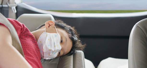 asian boy wear protet mask from coronavirus covid 19 epidermic in car while travel outside new normal lifestyle with boring expression stock photo