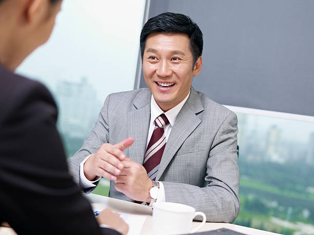 asian business people asian businessman discussing business with colleague in office, looking excited. click for more: china east asia photos stock pictures, royalty-free photos & images