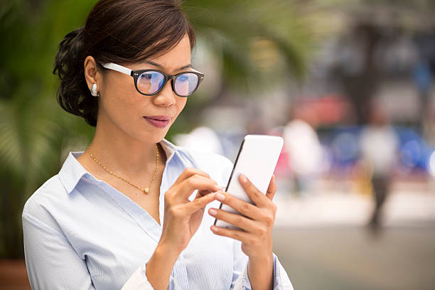 Asian Business Woman Smart Phone Asian woman text messaging on a smart phone. mobile real estate stock pictures, royalty-free photos & images