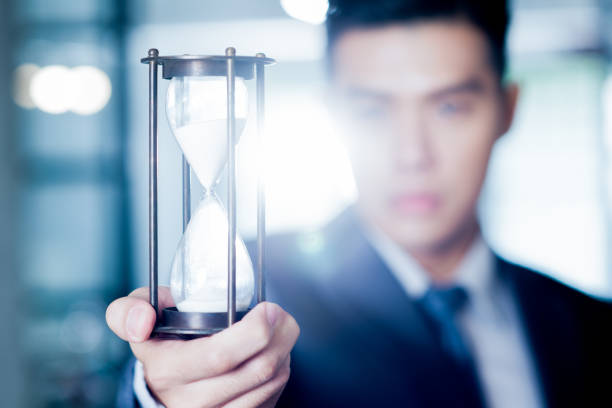 Asian businessman holding hourglass. stock photo