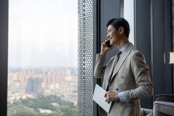携帯電話を使ったアジアのビジネスマン - business ストックフォトと画像