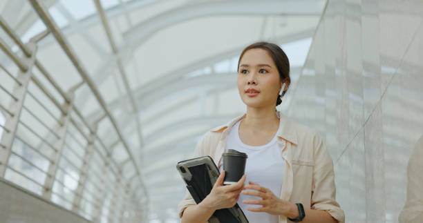 Asian businesswoman using Bluetooth headphones for conferences while commuting in transportation to work with happy smile. women use urban transport routes free internet technology in the city stock photo