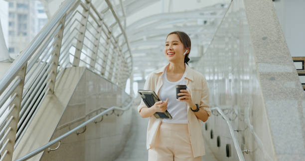 Asian businesswoman using Bluetooth headphones for conferences while commuting in transportation to work with happy smile. women use urban transport routes free internet technology in the city stock photo