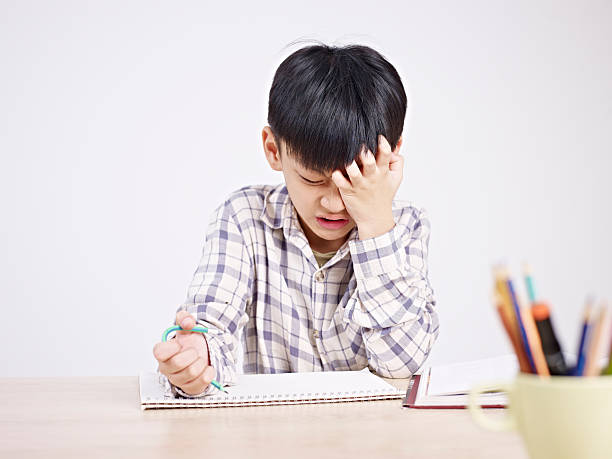 asian child frustrated 10 year-old asian elementary schoolboy appears to be frustrated while doing homework. asian depressed stock pictures, royalty-free photos & images