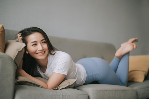 asian chinese beautiful woman lying down on sofa relax taking a break after workout in the morning