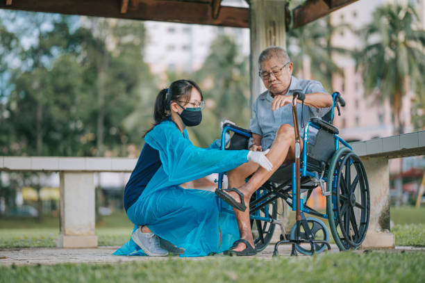 asian chinese female physical therapist guiding senior man in wheelchair stretching exercising his leg asian chinese female physical therapist guiding senior man in wheelchair stretching exercising his leg diabetic foot stock pictures, royalty-free photos & images