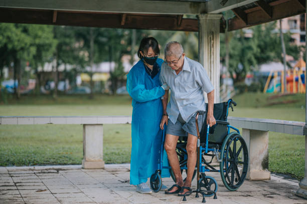asian chinese female physical therapist helping senior man get up from wheelchair and walking  in public park with crutch asian chinese female physical therapist helping senior man get up from wheelchair and walking  in public park with crutch diabetic foot stock pictures, royalty-free photos & images