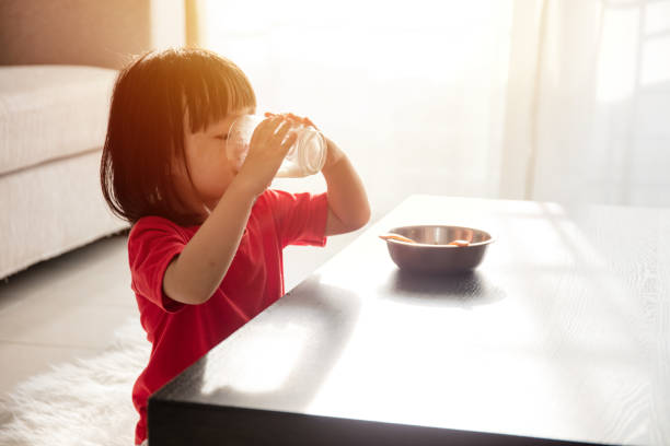 Asian Chinese little girl having breakfast with milk Asian Chinese little girl having breakfast with milk  in the living room at home drinking milk stock pictures, royalty-free photos & images