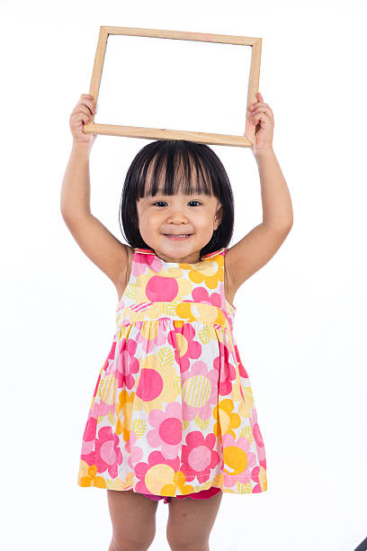 Asian Chinese little girl holding blank whiteboard stock photo