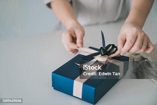 istock asian chinese mid adult woman receiving and opening gift at kitchen counter 1309429506