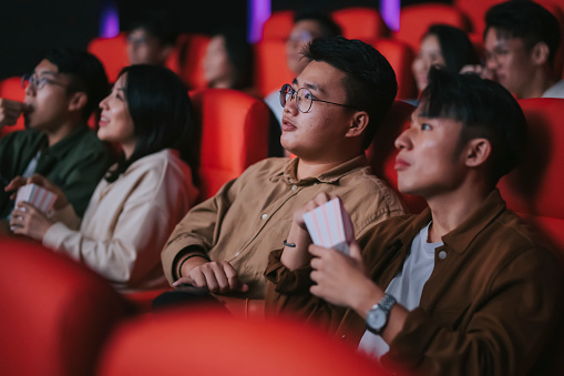 asian chinese mixed age group audience watching movie sitting in a row in cinema movie theater enjoying