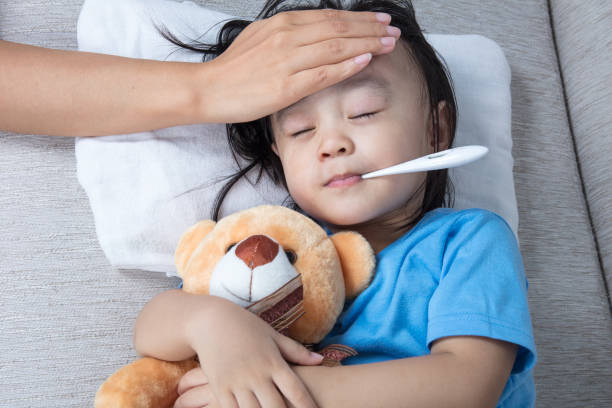 Asian Chinese mother measuring little girl forehead for fever stock photo
