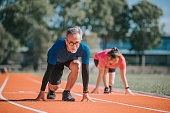 istock asian chinese senior couple getting ready to sprint at track and field stadium in the morning 1327476803