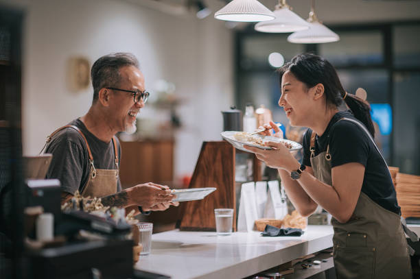 asian chinese senior male cafe owner and his daughter laughing while  taking a break enjoying dinner at bar counter coffee shop  after work - saki baba stok fotoğraflar ve resimler