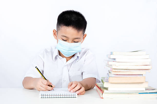 Asian Chinese Student Boy Writing with Protection Mask stock photo