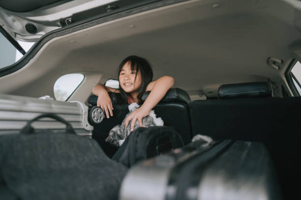 asiatica cinese giovane ragazza desiderosa di guardare avanti un viaggio con la sua famiglia guardando attraverso backseat dall'auto interna - scarico auto foto e immagini stock