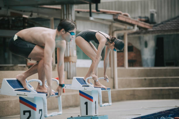 asian chinese young sportperson getting ready to dive into water on swimming starting block asian chinese young sportperson getting ready to dive into water on platform asien startblock stock pictures, royalty-free photos & images