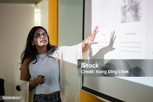 istock Asian college student is making a presentation in front of projector screen 1320658267
