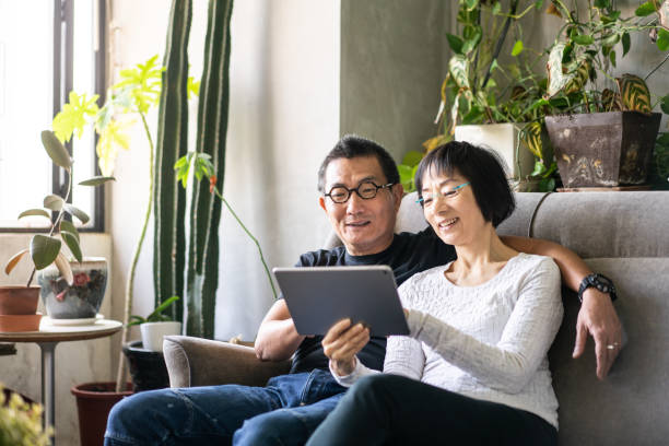 Asian couple using a digital tablet on sofa stock photo