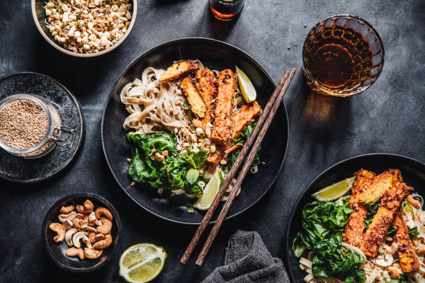 Asian cuisine served on a table Directly above shot of a lunch served on black table with chopsticks and a glass of whiskey. Top view of vegan Asian cuisine served on a table. asian food stock pictures, royalty-free photos & images