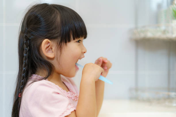 Asian cute child girl or kid brushing her teeth by toothbrush in the bathroom. Dental hygiene Healthcare concept. stock photo