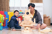 アジアのお父さんと息子は自宅で木製のビルディングブロックのおもちゃで遊んで楽しんで、幸せな父と幼稚園の男の子が一緒に質の高い時間を過ごす、教育玩具のコンセプト