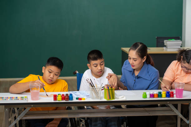 Asian disability kid and autism child learning arts in classroom with teacher Asian Autism children learning drawing art in classroom with female teacher autistic not smiling stock pictures, royalty-free photos & images