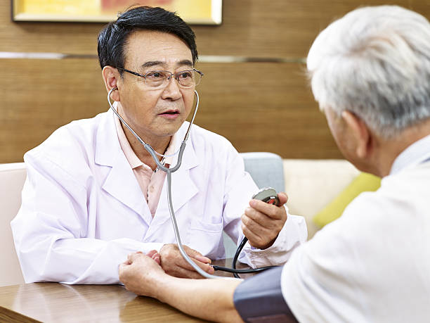 asian doctor checking blood pressure of a senior patient asian doctor measuring blood pressure of a senior patient using sphygmomanometer korean culture photos stock pictures, royalty-free photos & images
