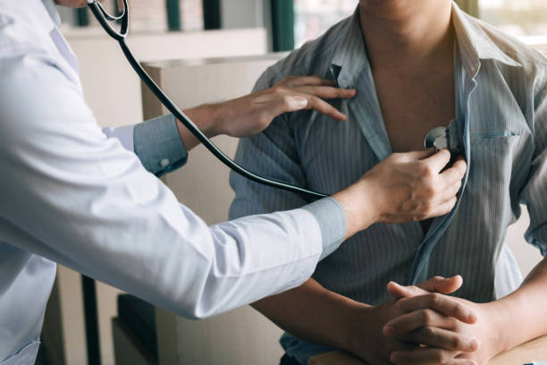 asian doctor is using a stethoscope listen to the heartbeat of the elderly patient. - médico a examinar paciente imagens e fotografias de stock