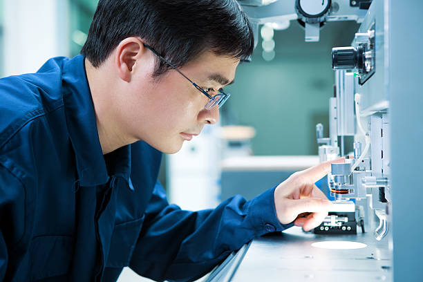Asian Electronics engineer tinkering with equipment stock photo