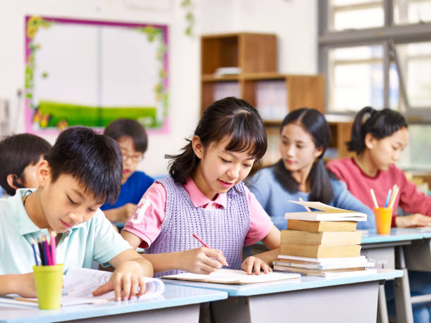 asian elementary school students in class group of asian primary school boys and girls studying in class. asian students young stock pictures, royalty-free photos & images