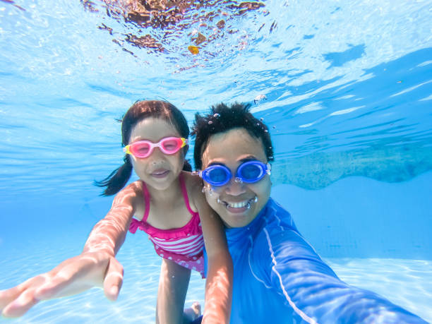 asian family in swimming pool asian cute daughter and father play and selfie happily in the swimming pool swimming goggles stock pictures, royalty-free photos & images
