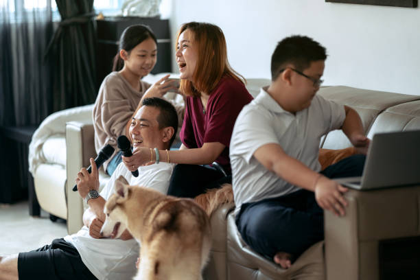 Asian family of four and two pet dogs spending time together stock photo