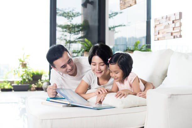 Asian family reading a book together at home. stock photo