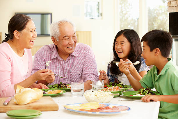 Asian family sharing meal at home Asian family sharing meal at home laughing asian family eating together stock pictures, royalty-free photos & images