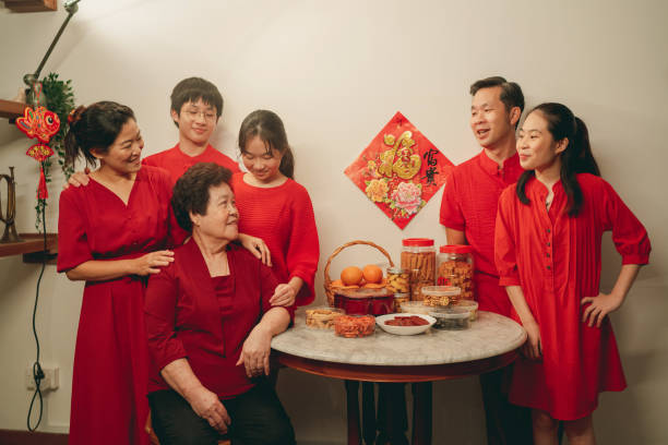Asian family wearing red candidly standing around a table with Chinese New Year table before taking the family portrait photo stock photo